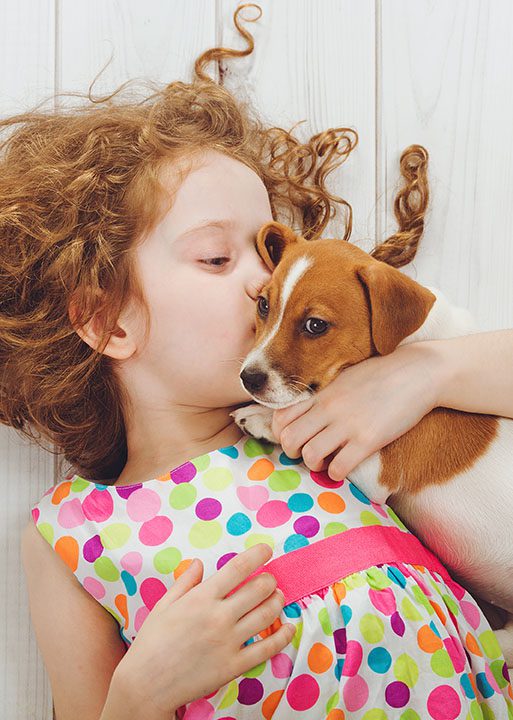 girl laying down hugging terrier puppy